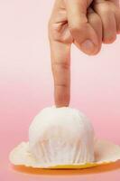 Hand touching delicious strawberry daifuku, Japanese rice cake against pink background photo