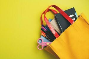 aprendizaje suministros con cuadernos, de colores plumas y tijeras en amarillo bolso foto