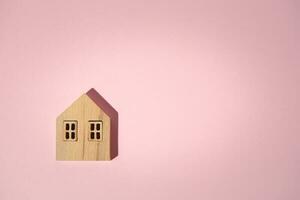 Wooden house model on pink background photo