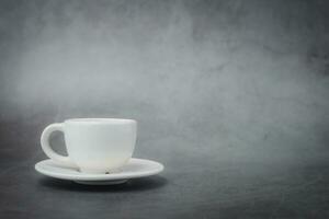 White cup of coffee with saucer on dark background photo