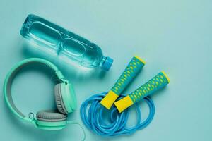 Fresh drinking water, jump rope and headphones on blue background photo