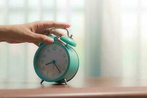 The bell alarm clock is turned off by hand in the morning photo