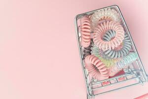 The shopping cart of spiral hair rubber bands on pink background photo