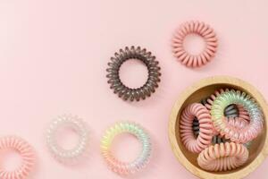 The wooden bowl of spiral hair rubber bands on pink background photo