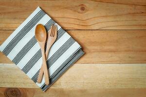 Spoon and fork with napery on wooden table photo