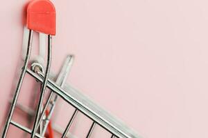 Close up of shopping cart or trolley on pink background photo