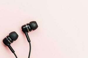 Black earphones on pink background photo