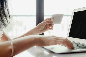 Woman's hand holding a credit card and using computer for online shopping and payment photo