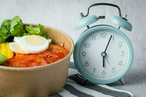 Fresco sano ensalada con un alarma reloj foto