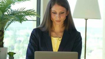 un mujer en lentes es mirando a su ordenador portátil trabajando dentro moderno oficina video