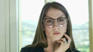 a woman in glasses is looking at her laptop working inside modern office video