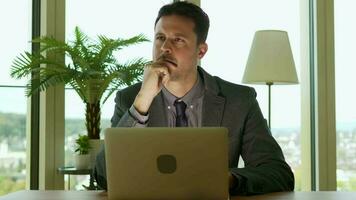 a man in a suit is sitting at a desk with a laptop working inside modern office video