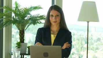 a woman in glasses is looking at her laptop working inside modern office video