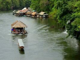 Floating house dragging by boat, Kanchanaburi, Thailand photo