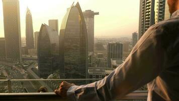 Young Business Man Standing on Balcony of Modern High Rise Apartment Overlooking Futuristic Cityscape Skyline video