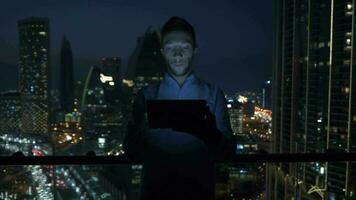 a man is using his tablet at night inside modern city apartment with skyline view video