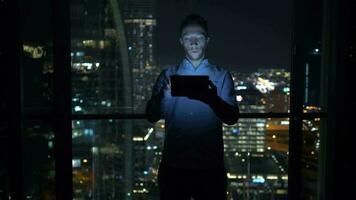 a man is using his tablet at night inside modern city apartment with skyline view video