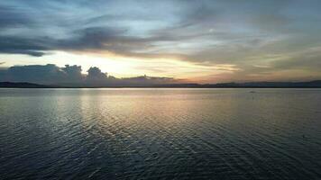 Aerial view over the water of the lake with sunset views and sun reflections. Aerial view of lake. Flying over water. Flight over calm lake surface video