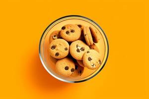 A glass bowl filled with chocolate chip cookies on a solid color background. photo