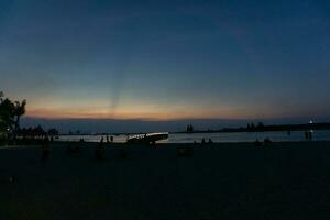 The sight of a beach during sunset, with a ship anchored along the coastline. photo