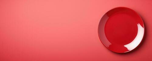 Vivid red round plate isolated on red background with a copy space, top view photo