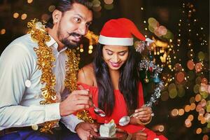 a man and woman in santa hats are eating a cake photo