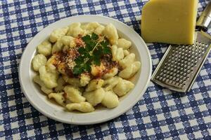 plato de hecho en casa Ñoquis con rallado queso en el mesa foto