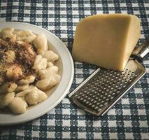 Plate of homemade gnocchi with grated cheese on the table photo