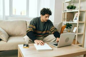 Man house online freelance business smile sitting typing internet working laptop computer home couch photo