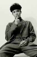 hombre pensativo estudiante confianza cigarrillo negro hipster Moda persona y moderno retrato sentado de fumar blanco foto