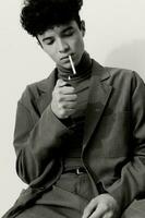 pensativo hombre de fumar Moda grave retrato y blanco cigarrillo estudiante sentado hipster negro foto