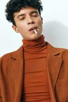Moda hombre sentado retrato de fumar cigarrillo beige foto