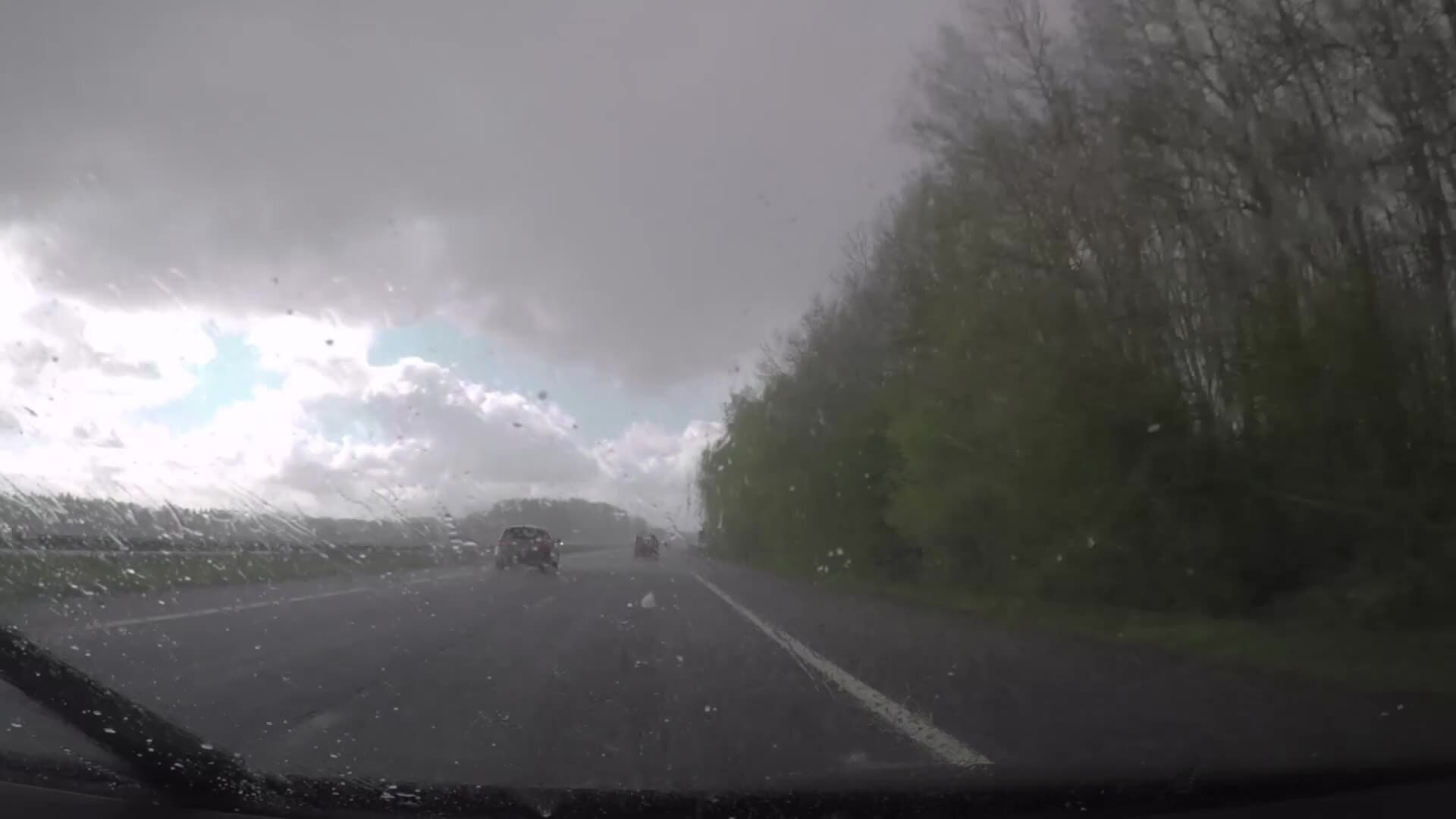 ливень. капли на стекле. дождливое окно из чёрной машины. колесо на асфальте. машина под дождем.