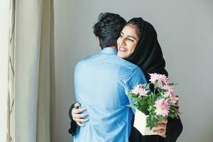 Happy muslim woman getting flowers as a gift from her relative on muslim celebration photo