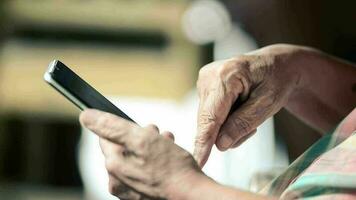 detailopname schot van een gerimpeld hand- van een ouderen vrouw wie is Aan een mobiel baan video