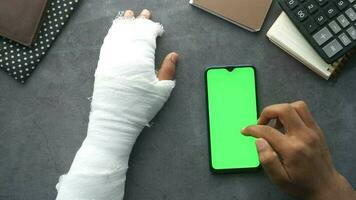 blessé douloureux main avec bandage et en utilisant intelligent téléphone video