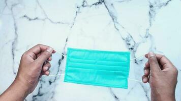 a person holding a blue surgical mask on a marble counter video
