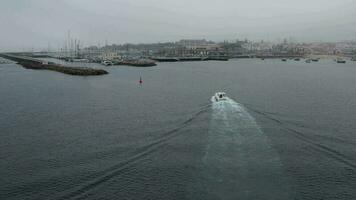 pov aérien drone vue suivi une excès de vitesse yacht sur une baie pendant une nuageux journée - capturé dans cascais, le Portugal video