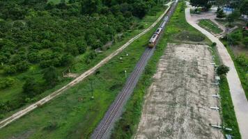 aéreo ver de un pasajero tren de viaje en el pistas en el campo en un soleado día. parte superior ver de Moviente tren en bosque. video