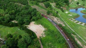 antenne visie van een passagier trein op reis Aan de sporen in de platteland Aan een zonnig dag. top visie van in beweging trein in Woud. video