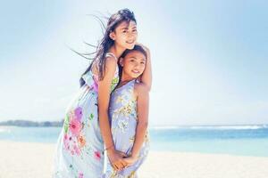 dos encantador asiático hermanas en un playa foto