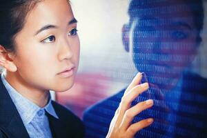 Young asian woman looking at the screen filled with machine code, 1 and 0 combinations photo