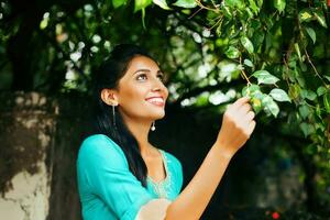 un mujer es sonriente y mirando a un árbol foto