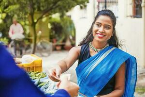 a woman in a sari is handing money to a man photo