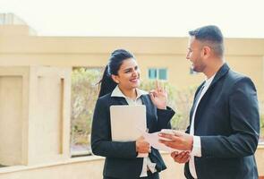 Business woman in suit showing ok sign to an indian man holding document. Approval concept photo