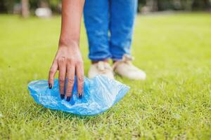 Dark skinned hand picking up plastic bag in the park photo