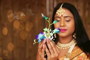 Beautiful Indian Hindu woman in traditional clothes holding an offering to God, meditating and praying photo