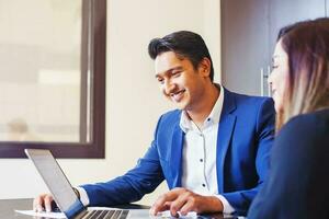 a man and woman in business attire are looking at a laptop photo