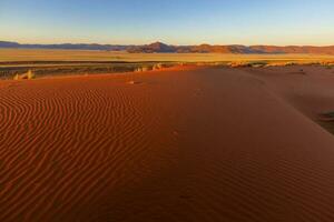 rojo arena duna a puesta de sol en namib Desierto foto