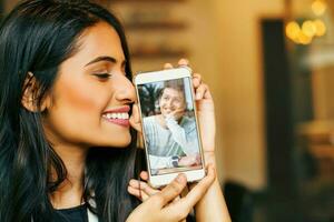 en línea Fechado joven indio mujer participación su teléfono con foto de su amado uno